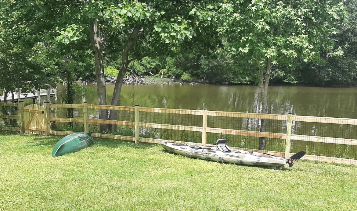 Pressure treated 3-rail ranch rail fence with black mesh and single arched gate