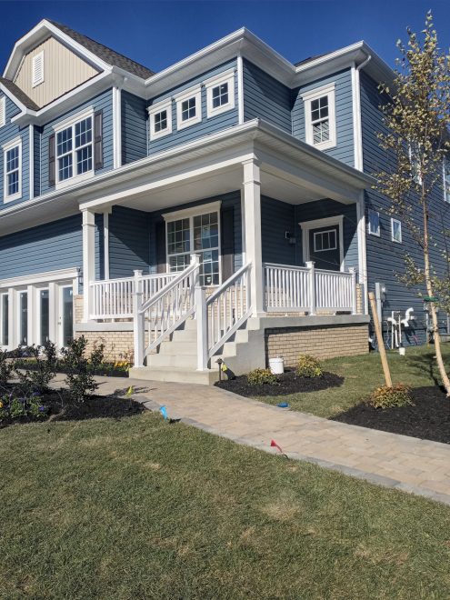 A front yard porch with white vinyl railing