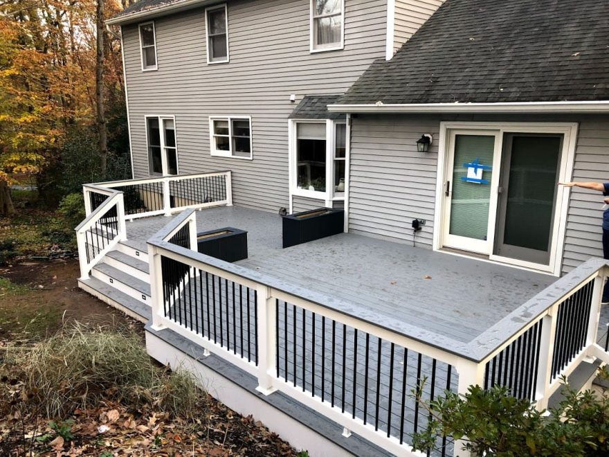 Trex Select Pebble Gray Decking with White Lincoln Vinyl Railing + Round Black Aluminum Balusters + matching Pebble Gray Cocktail Rail and two Composite Planters