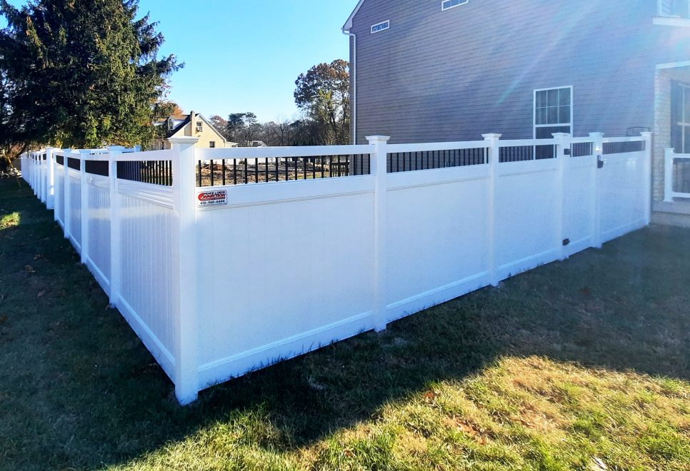 white vinyl privacy fence with black aluminum balsuter topper